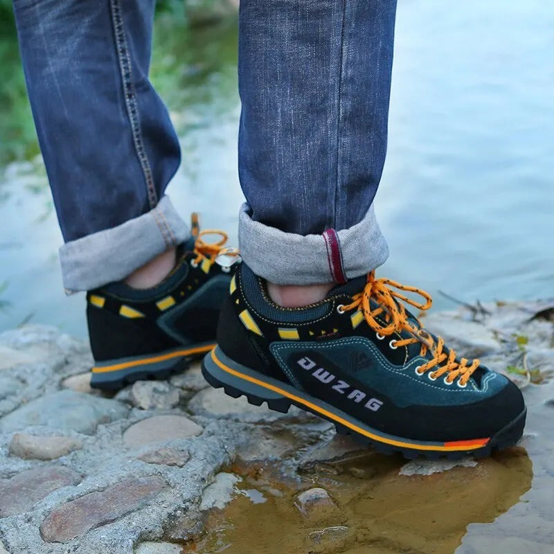 Chaussures de randonnée basses pour homme portées sur un rocher près de l’eau. Ce modèle offre une bonne adhérence sur terrain humide et irrégulier.
