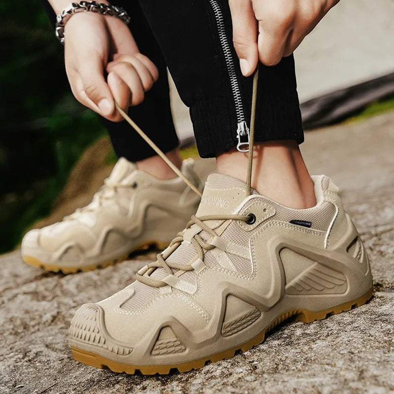 Chaussures de randonnée basses pour homme en beige en cours de laçage en extérieur. Ce modèle dispose d’une semelle crantée et d’un maintien optimal pour une utilisation sur terrain naturel.