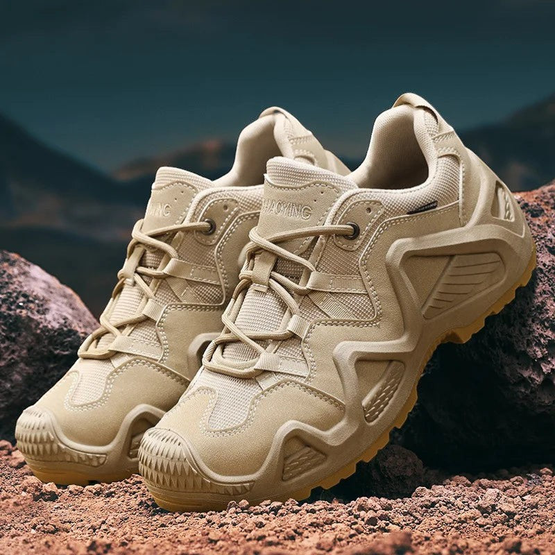Paire de chaussures de randonnée basses pour homme en beige posées sur un terrain rocheux en montagne. Ce modèle offre une semelle crantée pour une bonne accroche sur terrain naturel.