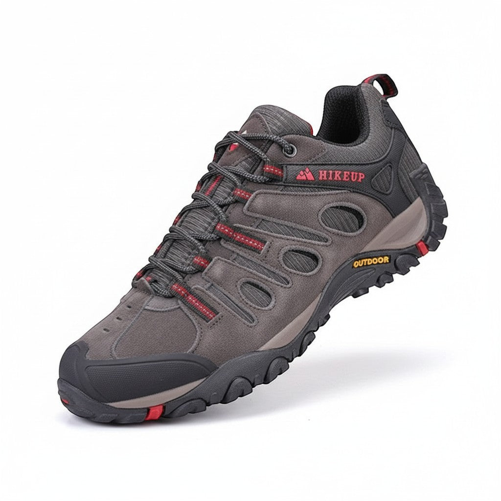Chaussures de randonnée basses pour homme en gris anthracite avec détails rouges sur fond neutre. Ce modèle léger est équipé d’une semelle crantée offrant une bonne accroche et une protection renforcée à l’avant.