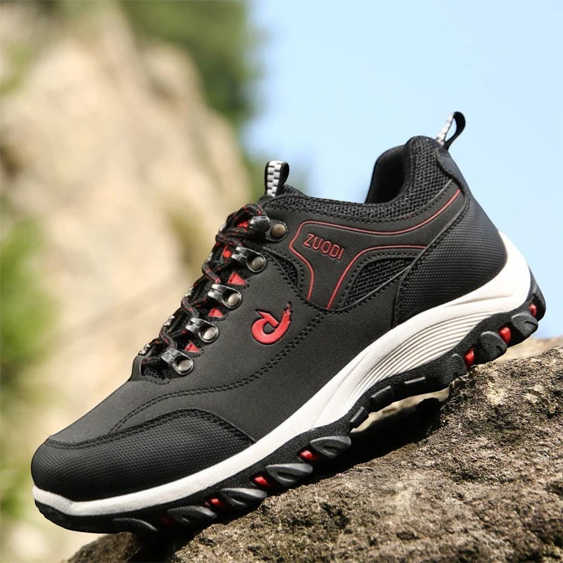 Chaussures de randonnée basses pour homme en noir posées sur un rocher. Ce modèle robuste est doté d’une semelle crantée assurant une bonne adhérence et une stabilité optimale.