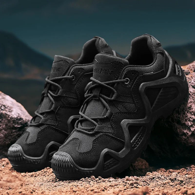 Paire de chaussures de randonnée basses pour homme en noir posées sur un sol rocheux. Ce modèle robuste est doté d’une semelle crantée assurant une bonne adhérence et une stabilité optimale.