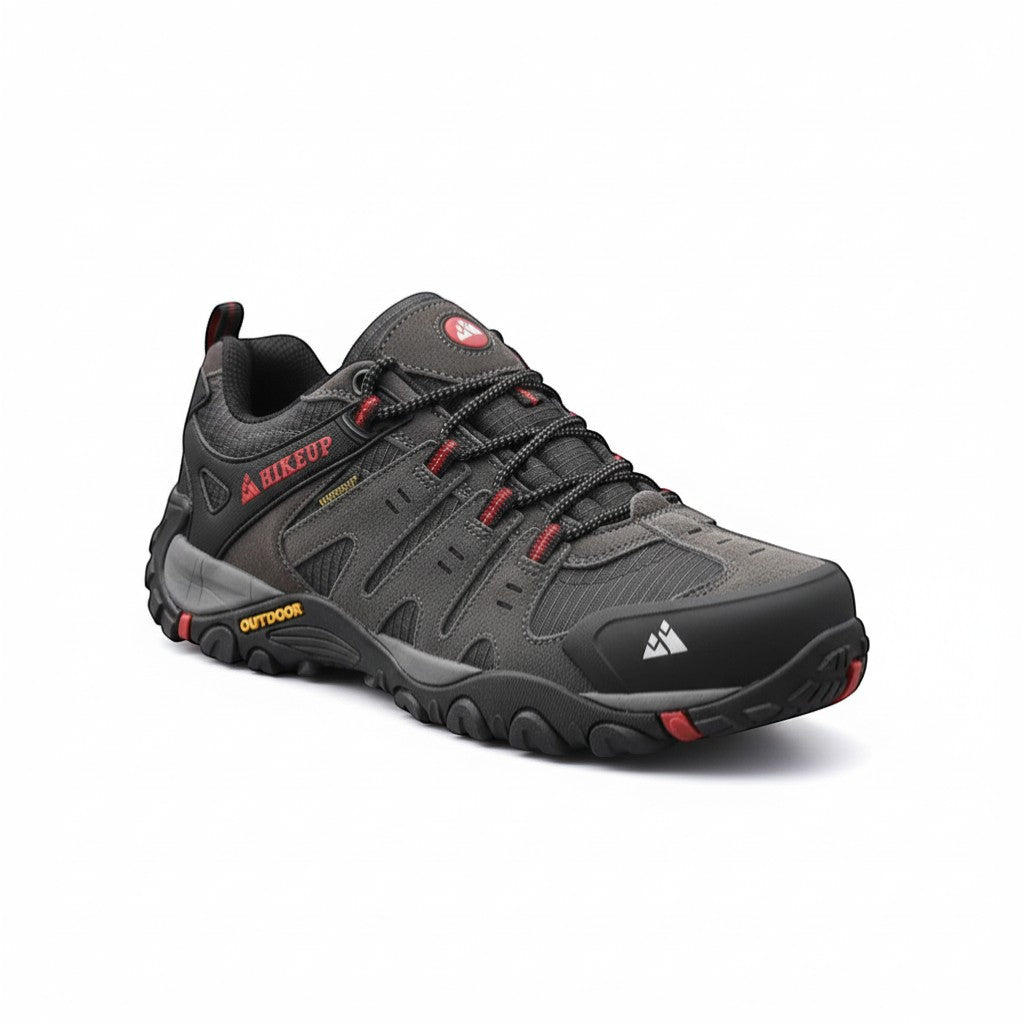Chaussures de randonnée basses pour homme en gris anthracite avec détails rouges sur fond neutre. Ce modèle léger est doté d’une semelle crantée offrant une bonne accroche, avec des renforts à l’avant pour plus de protection et de stabilité.