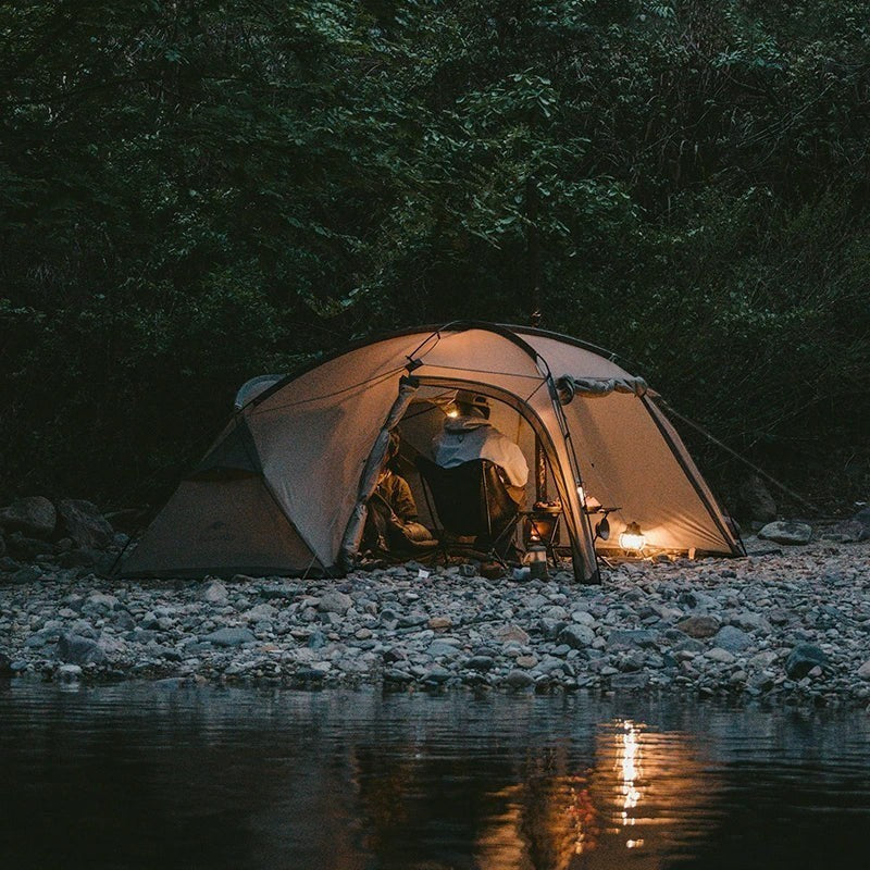 Tente de camping 4 saisons pour 2 personnes « Passion Randonnée », dotée d'une armature en aluminium et d'une toile enduite de silicone, installée au bord d'une rivière.