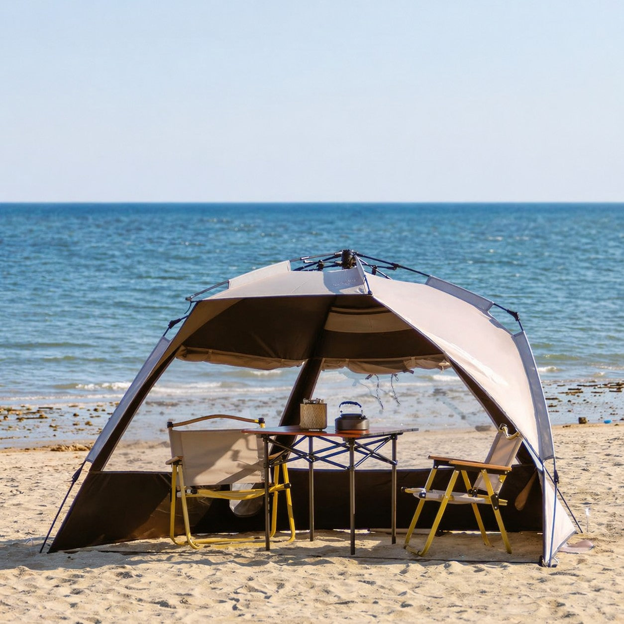 Tente de camping familiale automatique Passion Randonnée avec table et chaises sur une plage de sable.