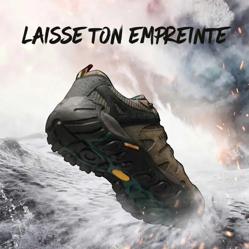 Vue rapprochée de la semelle extérieure crantée d'une chaussure de randonnée marron et noire, illustrant l'adhérence sur un terrain enneigé et escarpé.